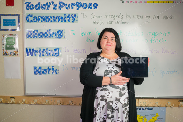 Education Stock Photo: Plus Size Elementary School Teacher Holding Tablet - Body Liberation Photos