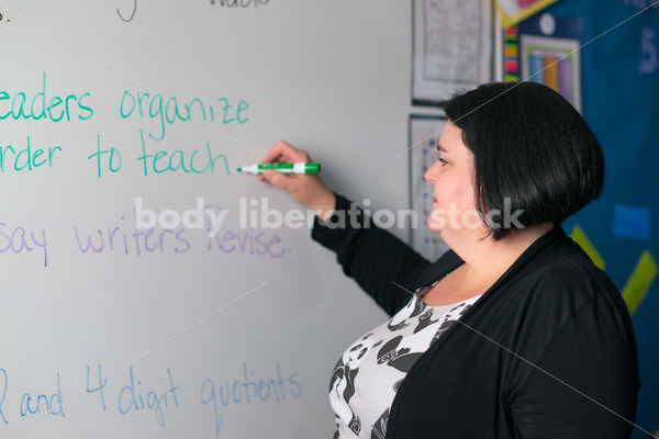 Royalty Free Stock Photo: Plus Size Teacher Writing on Whiteboard - Body Liberation Photos