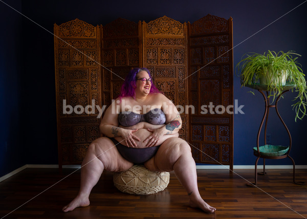 Fat-Positive Stock Photo: Plus-size Woman Posing Confidently on a Cushion Smiling to One Side